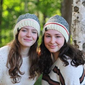 May include: Two people wearing crocheted hats with red, white, and blue stripes. The hats are made with a textured stitch and have a pompom on top.