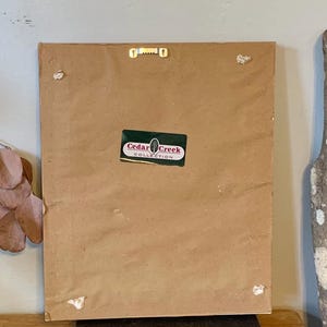 May include: The back of a framed picture with a brown paper backing. A sticker on the back reads "Cedar Creek Collection".