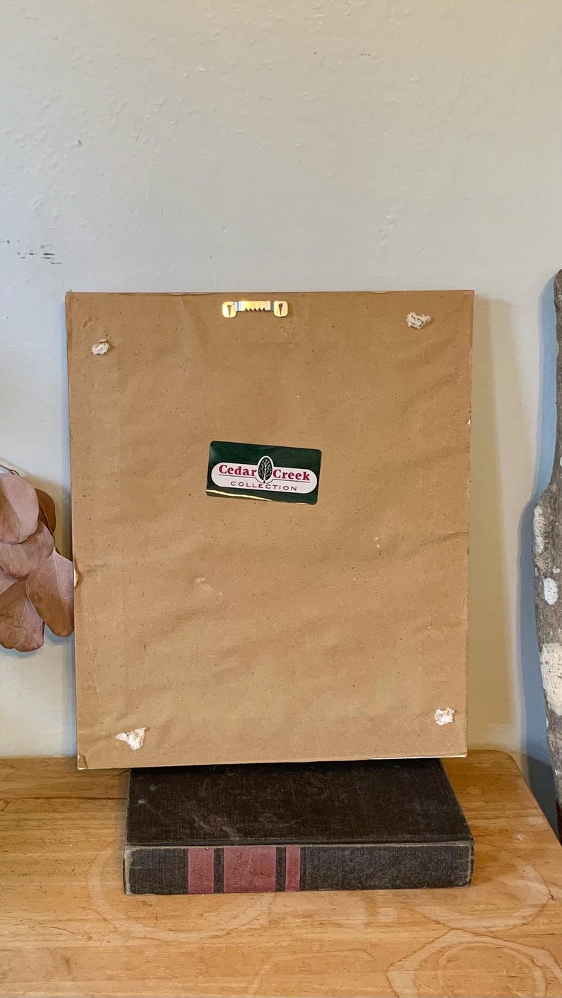 May include: The back of a framed picture with a brown paper backing. A sticker on the back reads "Cedar Creek Collection".