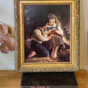 May include: A framed painting of two children sitting on a grassy knoll. The girl is wearing a blue dress and a blue ribbon in her hair. The boy is wearing a brown vest and a blue shirt. They are both looking at a small red object in the girl's hand.