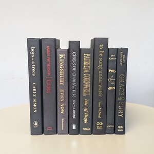 May include: A stack of ten black hardcover books with gold lettering on the spines. The titles include "Boys in the Trees", "Cross", "Even Now", "Crisis of Character", "Isle of Dogs", "to be sung underwater", "A Common Life", and "Grace and Fury".
