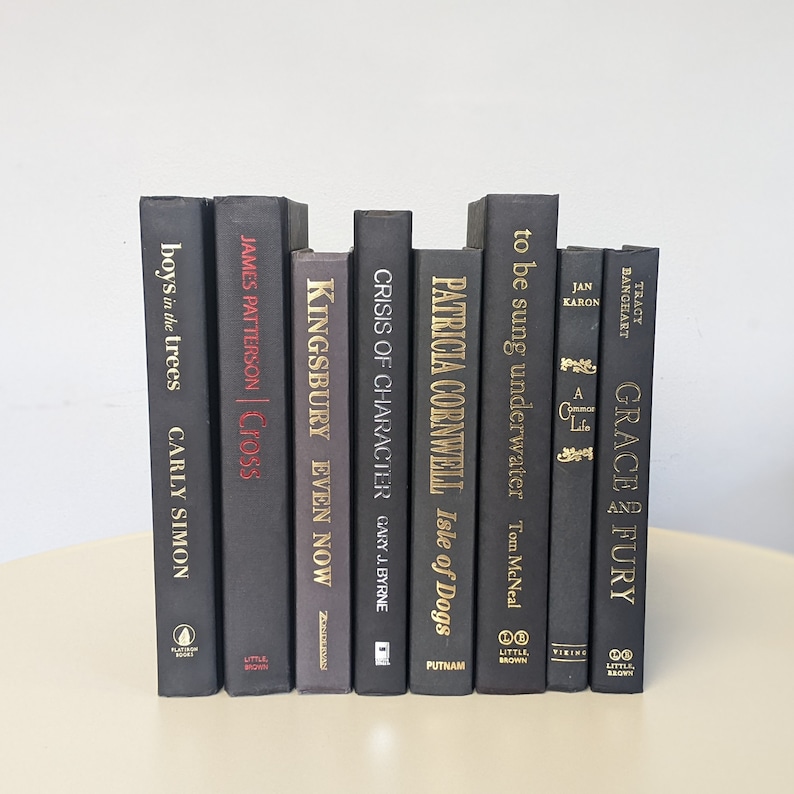 May include: A stack of ten black hardcover books with gold lettering on the spines. The titles include "Boys in the Trees", "Cross", "Even Now", "Crisis of Character", "Isle of Dogs", "to be sung underwater", "A Common Life", and "Grace and Fury".