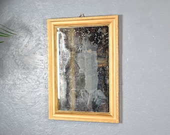 May include: A gold-framed mirror with a distressed, antique-style finish. The mirror has a rectangular shape and is hanging on a textured wall.