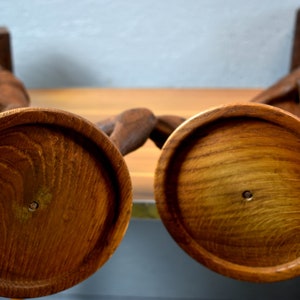 Puede incluir: Dos candelabros de madera con un dise&ntilde;o tallado. Los candelabros son marrones y tienen una base redonda.