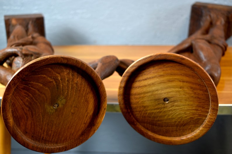 Puede incluir: Dos candelabros de madera con un dise&ntilde;o tallado. Los candelabros son marrones y tienen una base redonda.