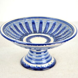 Puede incluir: Un cuenco de cerámica azul y blanco con pedestal y diseño de rejilla. El cuenco es perfecto para servir fruta o aperitivos.
