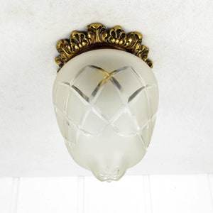 May include: A frosted glass ceiling light fixture with a decorative brass trim. The glass shade has a geometric pattern.