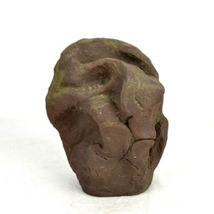 Könnte beinhalten: Eine braune Keramikskulptur mit einer rauen, strukturierten Oberfläche. Die Skulptur ist abstrakt und ähnelt einer Felsformation.