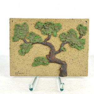 May include: A ceramic wall plaque with a textured, green tree design. The tree has a brown trunk and branches. The plaque is signed "Y. Gavin" in the lower left corner.