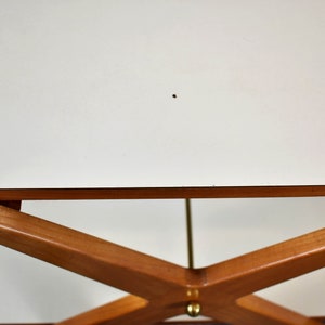 May include: A white table top with a wooden base. The base is made of four pieces of wood that are crossed in an X shape. The table is made of wood and has a white finish.
