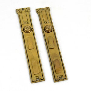 Puede incluir: Dos placas de dedo de puerta antiguas de latón. Cada placa es rectangular con un diseño floral decorativo en el centro y patrones geométricos en la parte superior e inferior. Las placas son de color dorado cálido.