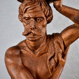 Puede incluir: Una escultura de madera detallada de un busto de hombre con un rollo en la cabeza. La escultura est&aacute; tallada en madera marr&oacute;n oscura y tiene un aspecto realista.