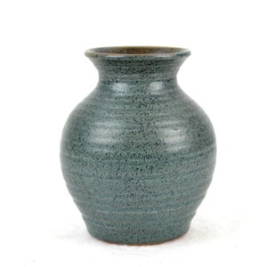 Könnte beinhalten: Eine kleine, runde, blaue Keramikvase mit einem gesprenkelten Überzug. Die Vase hat einen schmalen Hals und einen breiten Boden.
