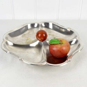 以下が含まれることがあります： 4つのセクションに分かれた銀製のサービングディッシュ。2つのセクションに赤いリンゴと赤いボールが入っています。