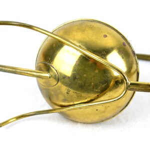May include: A brass watering can with a long spout and a handle. The can has a rounded shape and a shiny finish.
