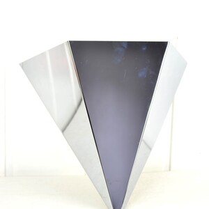 May include: A silver, triangular-shaped vase with a shiny, reflective surface.