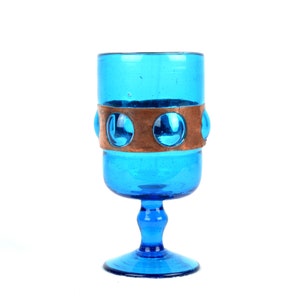 May include: A blue glass goblet with a copper band and circular accents around the middle.