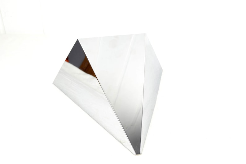 May include: A silver, geometric, triangular sculpture with a reflective surface.