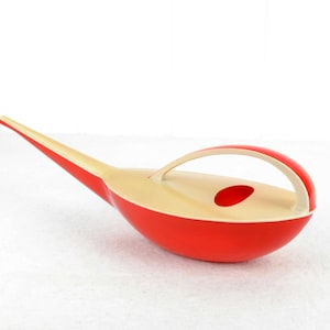 Könnte beinhalten: Eine rote und cremefarbene Gießkanne aus Kunststoff mit einem langen Auslauf und einem Griff. Die Gießkanne ist im Stil der Moderne der Mitte des Jahrhunderts gestaltet.