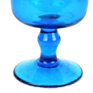 May include: A cobalt blue glass goblet with a wide bowl and a short stem. The goblet has a textured surface and a round base.
