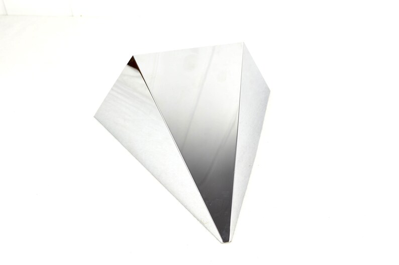 May include: A silver triangular shaped table with a reflective surface.