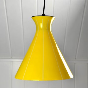 Könnte beinhalten: Eine gelbe Pendelleuchte mit weißen vertikalen Streifen. Die Leuchte hat einen breiten, ausgestellten Sockel und einen schmalen oberen Teil.