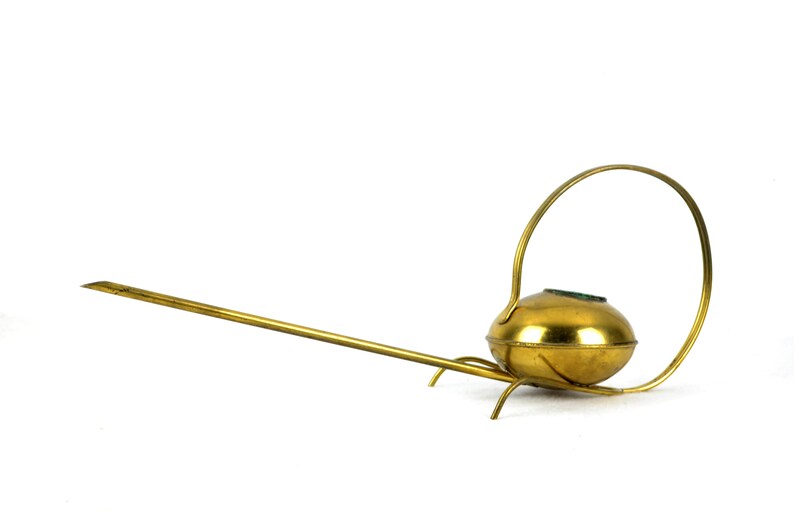 May include: A gold watering can with a long spout and a circular handle. The watering can has a round body and a small opening on the top.