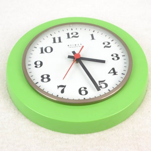 May include: A green and white round wall clock with black numbers and hands. The clock face has the text "WILMAR" in the center.