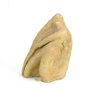 Peut inclure: Une sculpture en céramique beige représentant une personne assise, les bras croisés devant elle.