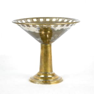 Puede incluir: Un cuenco de metal dorado con un diseño decorativo de corte alrededor del borde. El cuenco se asienta sobre un pedestal alto y delgado.