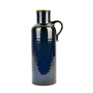 May include: A dark blue ceramic vase with a handle. The vase has a speckled glaze and a slightly rounded shape.