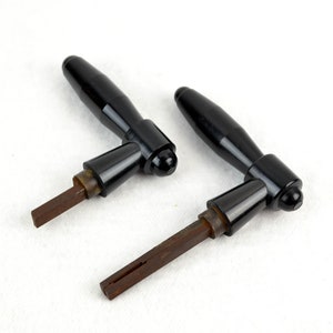 May include: Two black door handles with metal rods. The handles are made of a smooth, glossy material.