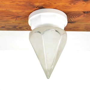 May include: A white ceiling light fixture with a frosted glass shade shaped like a diamond. The shade has a pointed tip and a white ceramic base.