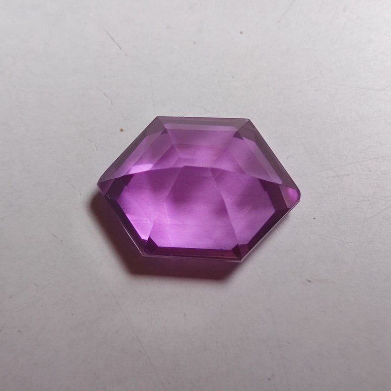 May include: A hexagonal purple gemstone with a faceted cut.