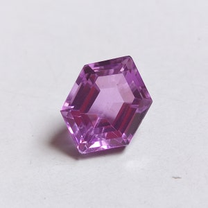 May include: A hexagonal cut amethyst gemstone with a purple hue.