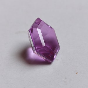May include: A purple faceted glass gem with a hexagonal shape.