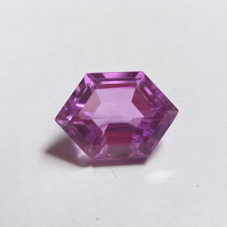 May include: A faceted purple gemstone with a hexagonal shape.