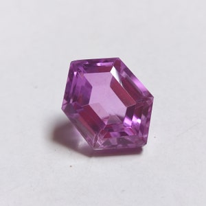 May include: A purple gemstone with a hexagonal cut and a faceted finish.
