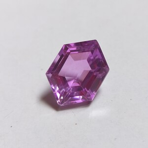 May include: A hexagonal cut purple gemstone with a faceted design.