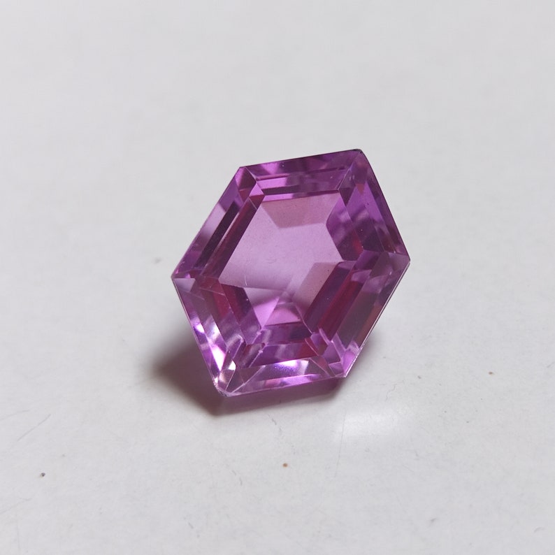 May include: A hexagonal cut purple gemstone with a faceted design.