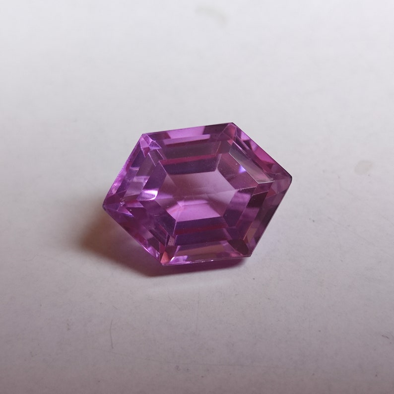 May include: A hexagonal cut, purple gemstone with facets.