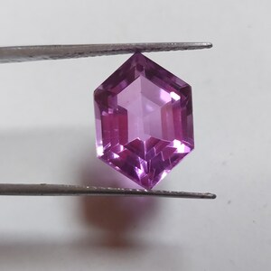 May include: A purple gemstone with a hexagonal shape and a faceted cut.