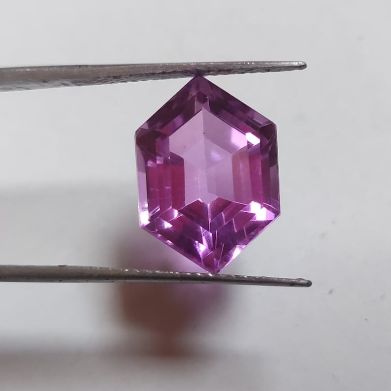 May include: A purple gemstone with a hexagonal shape and a faceted cut.