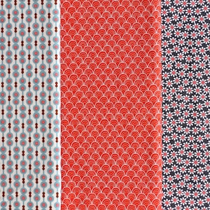 Könnte beinhalten: Drei Stoffmuster mit verschiedenen Mustern. Eines hat einen weißen Hintergrund mit einem sich wiederholenden Muster aus blauen Kreisen und braunen Punkten. Das zweite ist rot mit einem weißen Muscheldesign. Das dritte hat einen marineblauen Hintergrund mit weißen und roten Blumen.