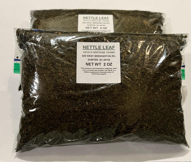 May include: Two clear plastic bags filled with dried nettle leaf. Each bag has a white label with the text "NETTLE LEAF" and "NET WT 2 OZ". The bags are sealed and appear to be ready for sale.