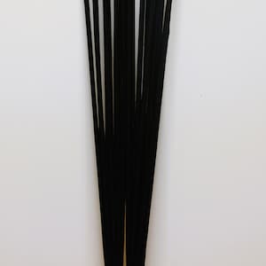 May include: A bundle of black incense sticks with a golden base. The sticks are tied together with a clear band.