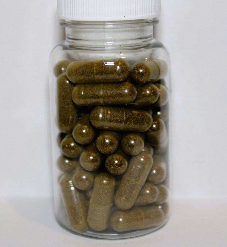 May include: A clear glass jar filled with brown capsules. The jar has a white lid.