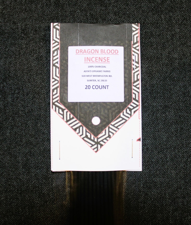 May include: A white package with black and white geometric designs. The package contains 20 Dragon Blood incense sticks. The package label reads "Dragon Blood Incense", "100% Charcoal", "Asya's Organic Farms", "320 West Brewington Rd.", "Sumter, SC 29153", and "20 Count".