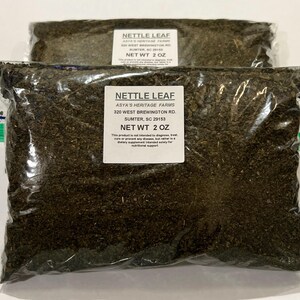 May include: Two clear plastic bags filled with dried nettle leaf. Each bag has a white label with the text "NETTLE LEAF" and "NET WT 2 OZ". The labels also include the seller's farm name and address.