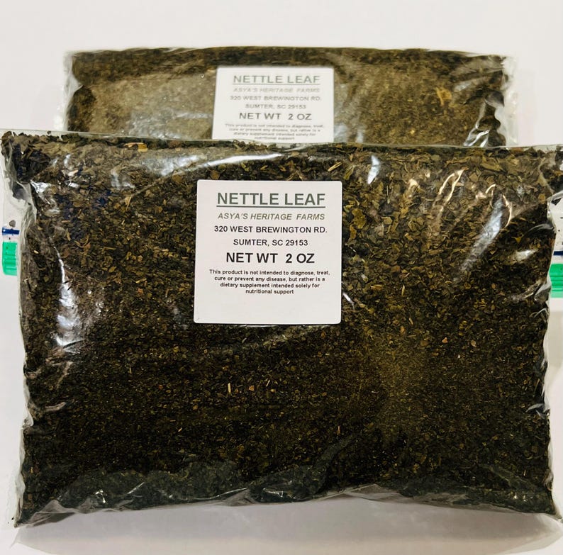 May include: Two clear plastic bags filled with dried nettle leaf. Each bag has a white label with the text "NETTLE LEAF" and "NET WT 2 OZ". The labels also include the address of Asya's Heritage Farms in Sumter, SC.